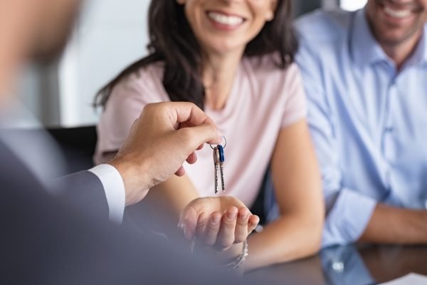 Real estate agent giving house keys to woman